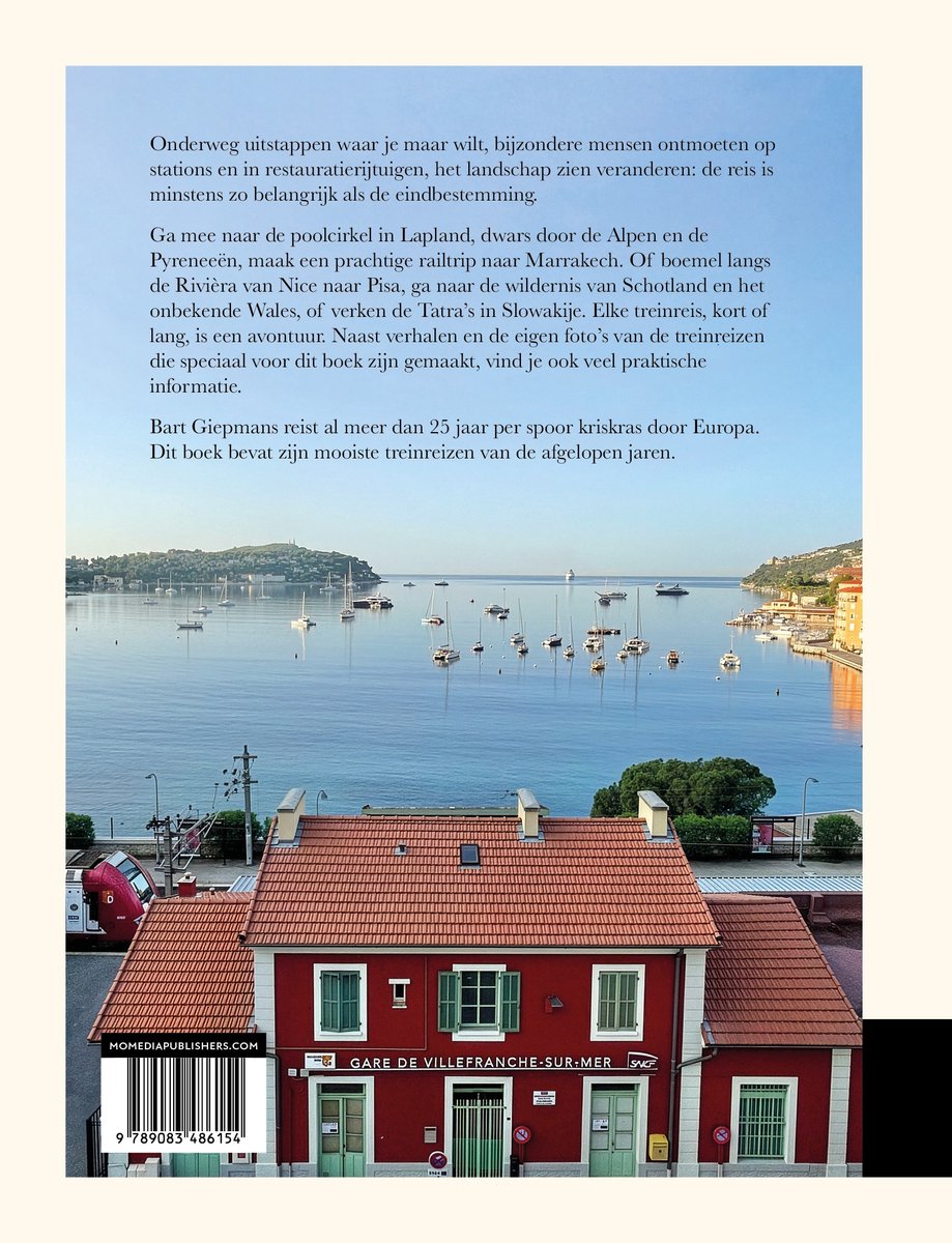 Rode treinwagon bij het station van Villefranche-sur-Mer met boten in de haven op de achtergrond.