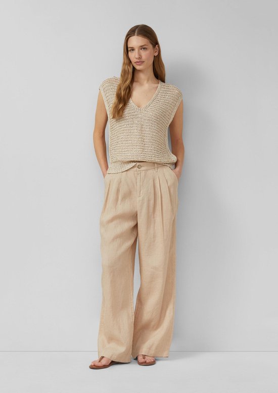 Model draagt een beige gebreide top en een wijde beige linnen broek.