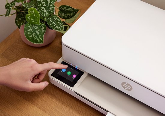 Vinger drukt op kleuren-touchscreen van een witte HP Envy printer.