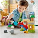 Een jongetje speelt met LEGO Duplo blokken, waaronder een rode en blauwe dinosaurus, groene goblin en een fort.