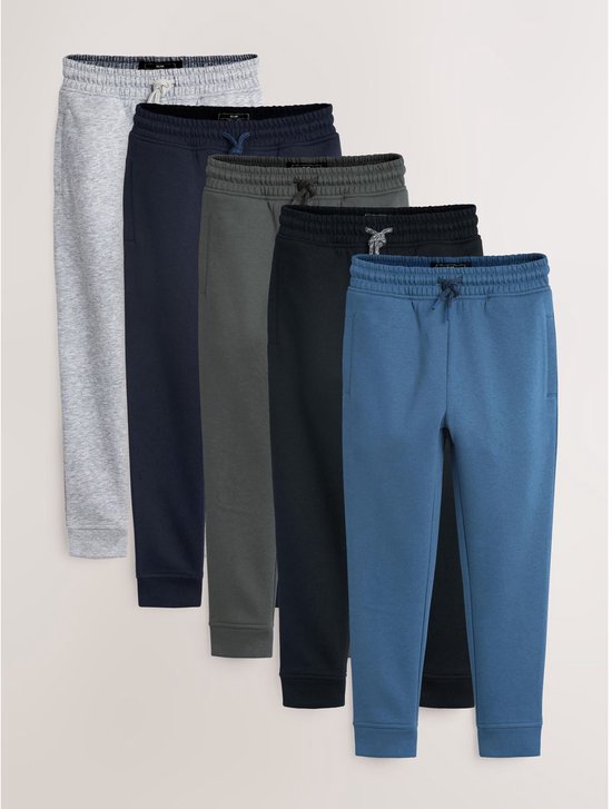 Vijf joggingbroeken in verschillende kleuren: grijs, donkerblauw, grijsgroen, zwart en petrolblauw.
