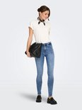 Model in blauwe skinny jeans met middelhoge taille, wit T-shirt en zwarte loafers.