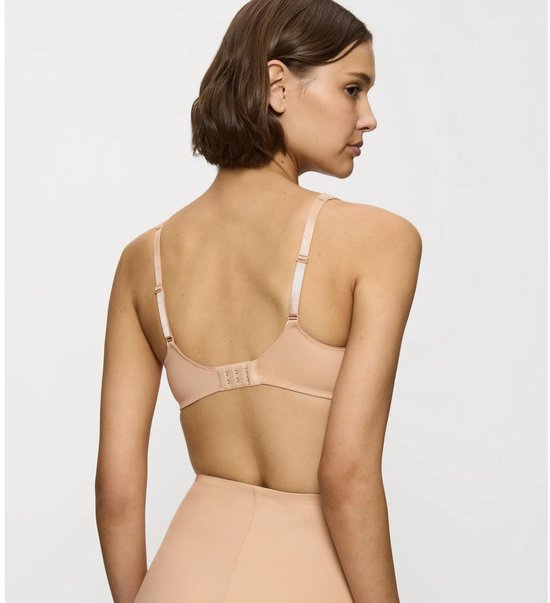 Model van achteren gezien, draagt huidkleurige beugelbeha met beige bandjes en sluiting.