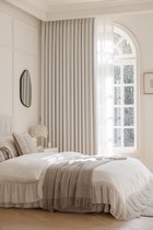 Slaapkamer met een hemelbed, een raam met gebogen bovenkant en gebroken witte, gestreepte gordijnen.