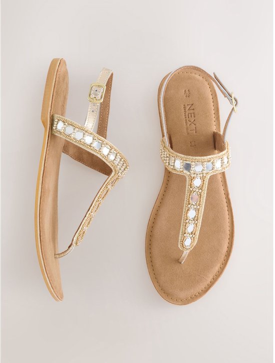 Gouden sandalen met platte zool, versierd met parels en spiegeltjes op de bandjes.