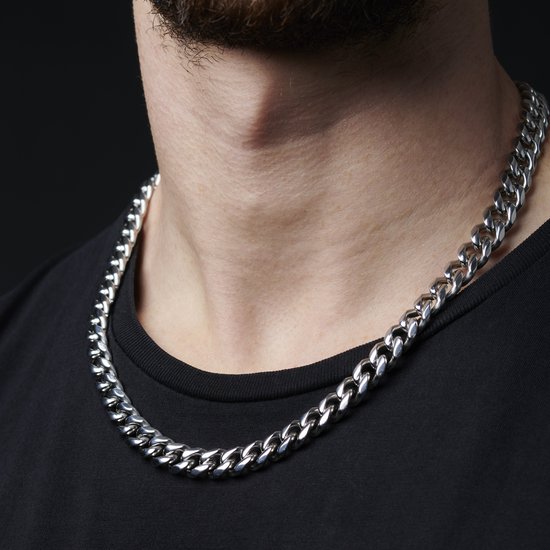 Zilverkleurige schakelketting gedragen door een man met zwarte T-shirt.