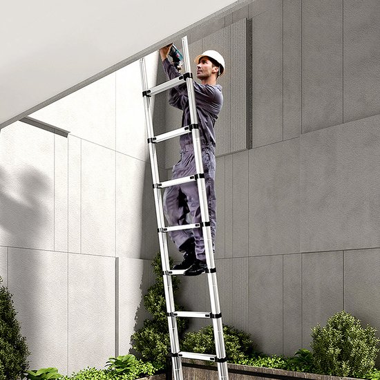 Man in overall en helm werkt met boormachine aan een gevel, staand op een opengevouwen ladder.