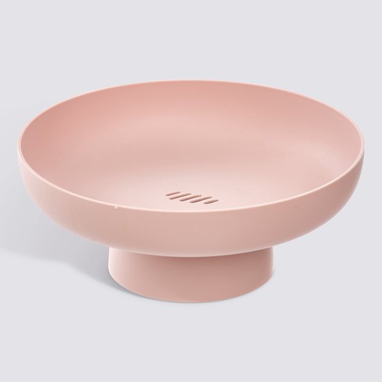 Roze fruitschaal op voet met een lichte schaduw op een grijze achtergrond.