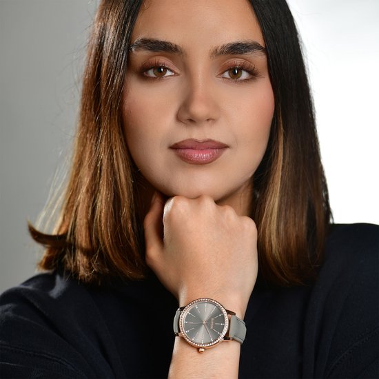 Vrouw met bruin haar draagt een Raptor horloge met grijze leren band en donkergrijze wijzerplaat.