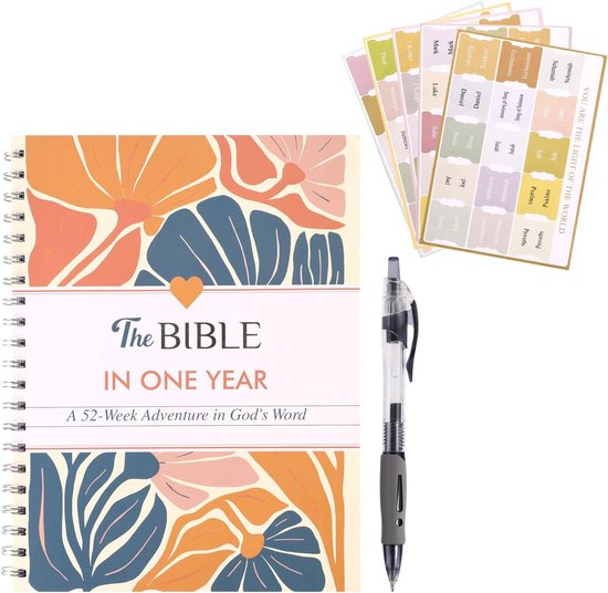 Een dagboek met de titel "The Bible in One Year", versierd met een bloemenpatroon in oranje, blauw en groen. Een pen ligt ernaast.