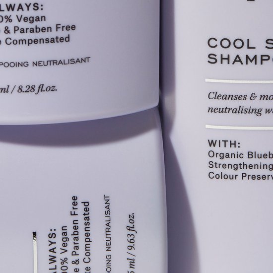 Close-up van witte flessen met paarse tekst 'Cool Silver Shampoo' en ingrediëntenlijst.