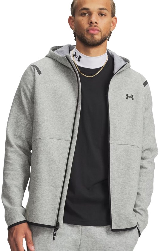 Man met grijze Under Armour hoodie met rits, zwart t-shirt, gouden ketting en grijs trainingspak.