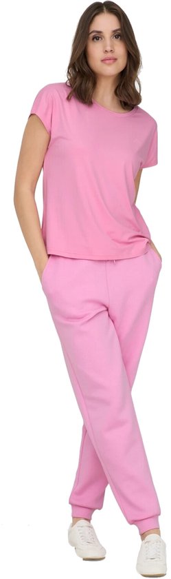 Model in roze Only Play T-shirt met korte mouwen en roze joggingbroek, met handen in de zakken.