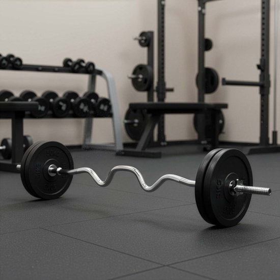 Een gebogen Actiget halterstang met ronde gewichtsschijven, staand op een zwarte fitnessvloer in een sportzaal.