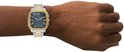 Zilverkleurig herenhorloge met gouden details op kast en schakelband. Blauw met Romeinse cijfers.