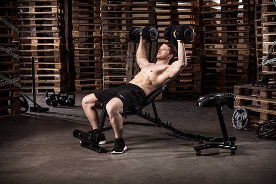 Man ligt op een fitnessbank en doet oefeningen met Tunturi verstelbare dumbbells.