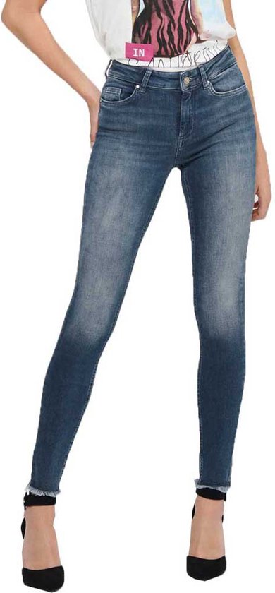 Model in wit T-shirt met print en donkerblauwe skinny jeans met rafelige zoom.