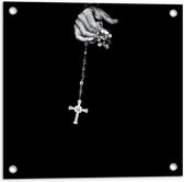 Tuinposter – Kruis aan Zilveren Ketting in Hand tegen Zwarte Achtergrond - 50x50 cm Foto op Tuinposter (wanddecoratie voor buiten en binnen)