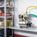 Gedetailleerde opname van een RVS hydrofoorpomp met gele motorbehuizing en drukvat, gemonteerd op een schap.