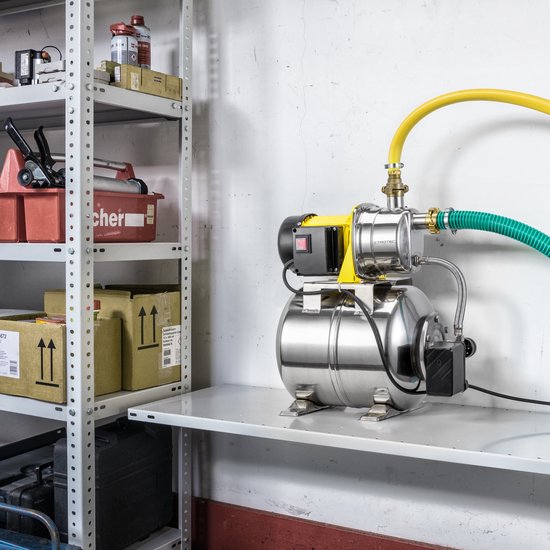 Gedetailleerde opname van een RVS hydrofoorpomp met gele motorbehuizing en drukvat, gemonteerd op een schap.