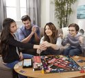 Familie speelt Monopoly Valsspelers Editie, met een handboei aan de pols.