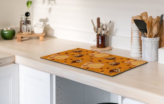 Oranje kookplaatbeschermer met koffiepatroon op een aanrecht.