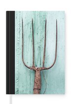 Notitieboek - Schrijfboek - Een roestige hooivork tegen een lichtblauwe achtergrond - Notitieboekje klein - A5 formaat - Schrijfblok