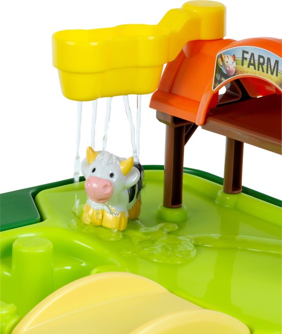 Close-up van een speelgoedkoe die nat wordt onder de watergoot van de John Deere boerderij speeltafel.