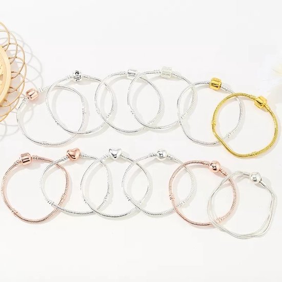 Verschillende bedelarmbanden in zilver-, roségoud- en goudkleur, sommige met hartvormige bedels.