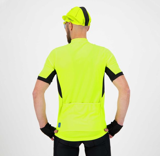 Man staat naar achteren, poseert met handen op heupen. Draagt fluorgeel fietsshirt met zwarte mouwen en zijkanten, zwarte fietsbroek en groene sokken.