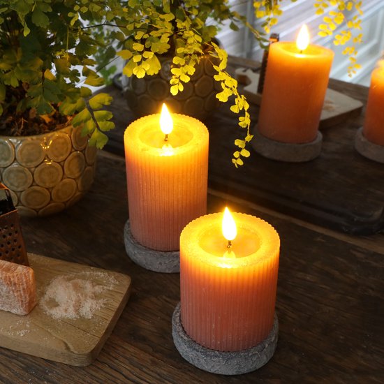 Twee mauve stompkaarsen met verticale ribbels en flakkerende LED-vlammen op een houten tafel.