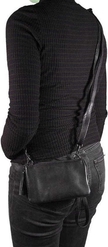 Zwarte leren clutch met franjes, gedragen als schoudertas door een model met jeans.