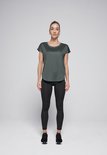 Vrouw staat frontaal, draagt een donkergroen shirt en een zwarte legging, met sportschoenen.