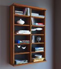 Une bibliothèque étroite et haute en bois brun foncé, montée sur un mur gris foncé. Les six étagères sont remplies de livres, CD et décorations.