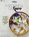 Gouden schaal met een dessert met blauwe bessen en een paarse bloem. Een lepel met 'a spoonful of love' erop.