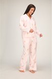 Model draagt een roze pyjamaset met hertjesprint, bestaande uit een pyjamabroek en bijpassend overhemd.