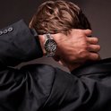 Persoon in zwart colbert met Citizen Tsuyosa horloge aan de pols, hand rustend op het achterhoofd.