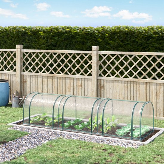 Transparante minikas met groenten in een tuin, omheind door een houten schutting.