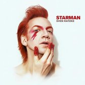 STARMAN SVEN RATZKE met rood haar, gezichtsmake-up met een bliksemschicht en rode glitter op de vingers.