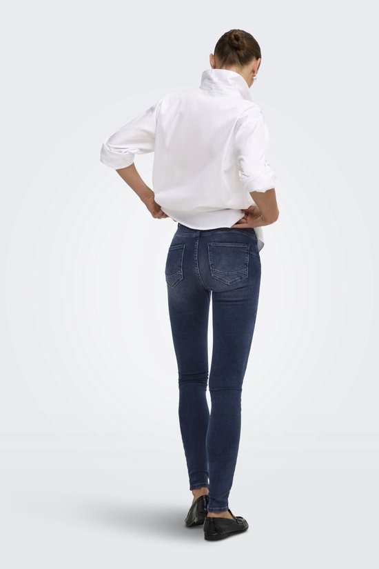 Achteraanzicht van een blauwe push-up skinny jeans, gecombineerd met een wit overhemd.