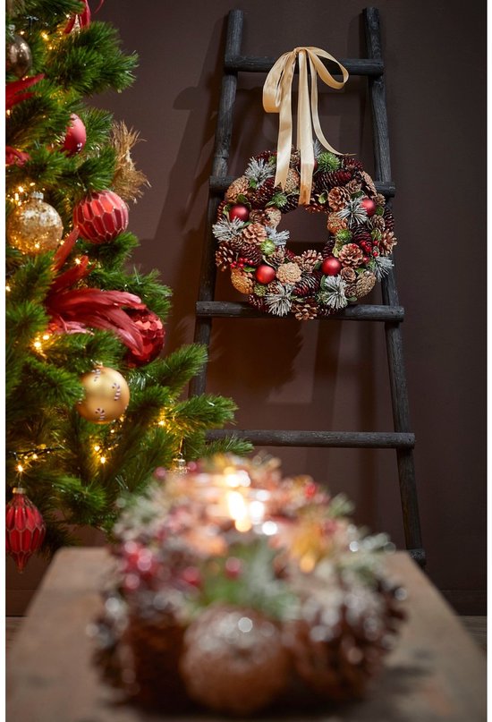 Zwarte decoratieladder met kerstkrans en strik, naast kerstboom