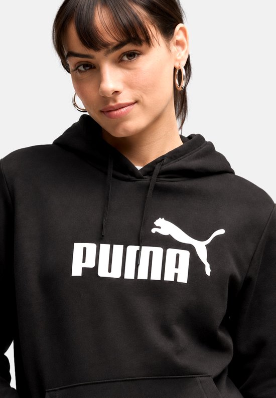 Dichtbij van een vrouw in een zwarte Puma hoodie met groot wit Puma-logo op de borst.