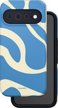 Blauw telefoonhoesje met golvend crème patroon dat over een zwarte binnenlaag wordt geplaatst.
