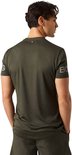 Donkergroen sportshirt van gerecycled polyester, met logo op de mouw. Man met handen in zakken.