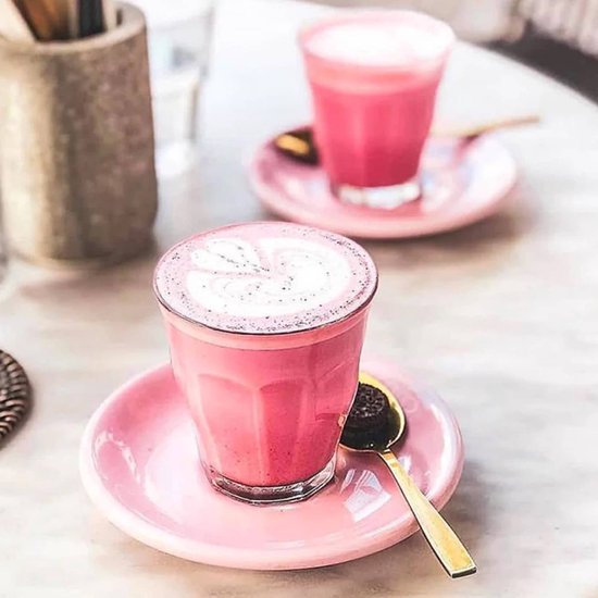 Twee glazen met roze drank en melkschuim op roze schotels.