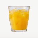 Verre Duralex Picardie rempli de boisson orange et de glaçons. Sur un fond clair.