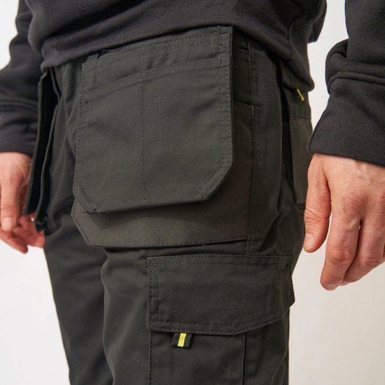 Close-up van de zwarte werkbroek met ruime zakken en geel detail.