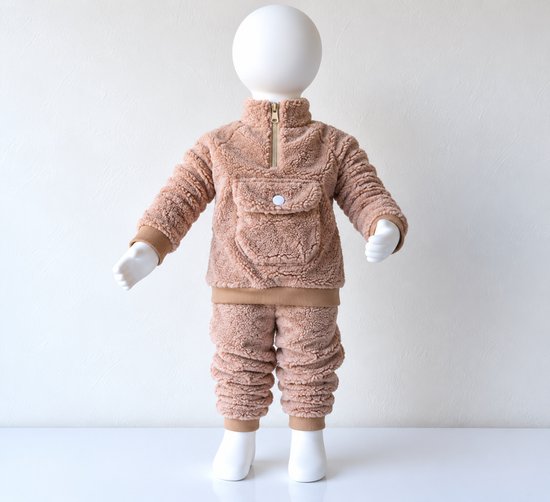 Bruine teddy-set op een etalagepop, tweedelig pakje met ritskraag en zakdetail op de borst.