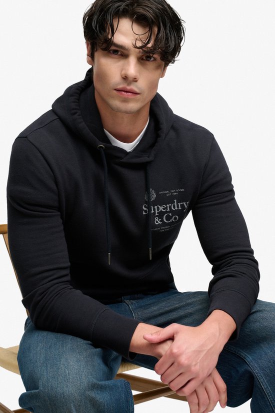 Close-up van model in donkerblauwe hoodie met 'Superdry & Co' logo.