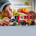 Jongen bouwt aan LEGO City snackwagen met frietjes; LEGO-poppetjes staan ernaast.